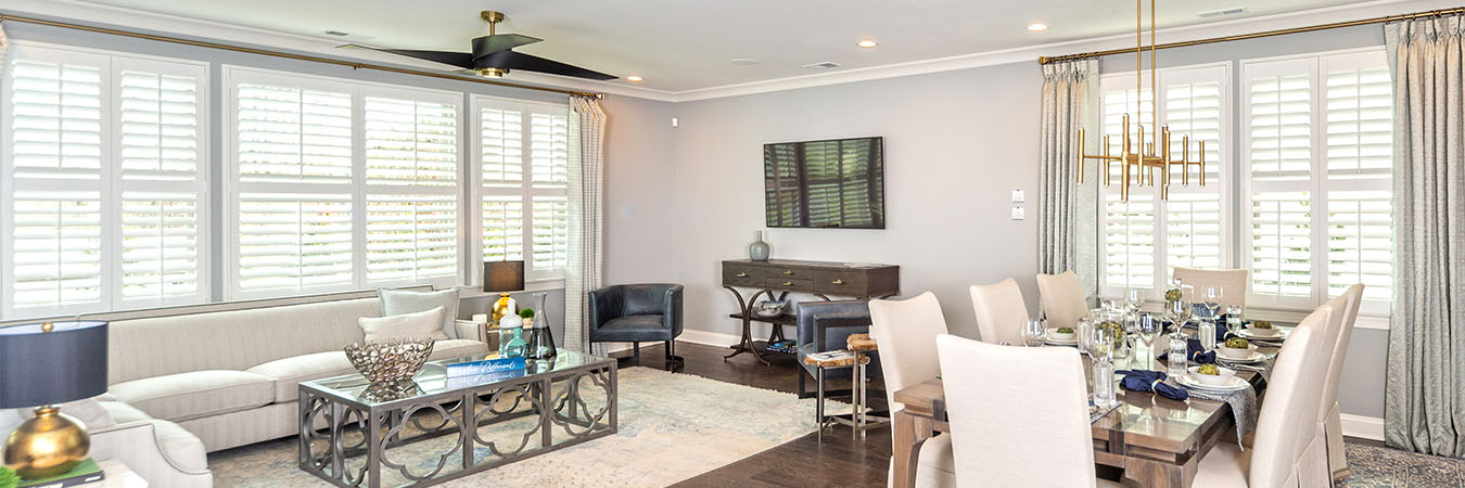 White Polywood shutters on windows in an open concept dining room/living room