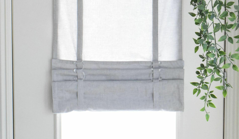 With a tiered tumble shade in Miami, you can block sun glare all year round. Gray rolled tumble shade on a glass door